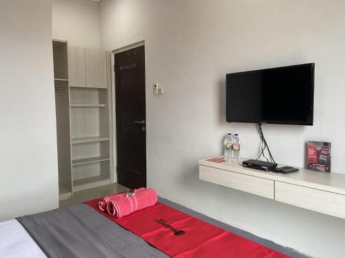 a room with a bed with a flat screen tv at RedDoorz near RSUD Margono Purwokerto 3 in Purwokerto