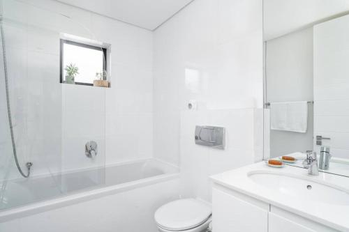 a white bathroom with a tub and a toilet and a sink at 16 on Sloane in Cape Town