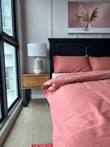 a bedroom with a bed with pink sheets and a window at Mont Kiara 163 Mall (The Ooak) Private Room in Kuala Lumpur