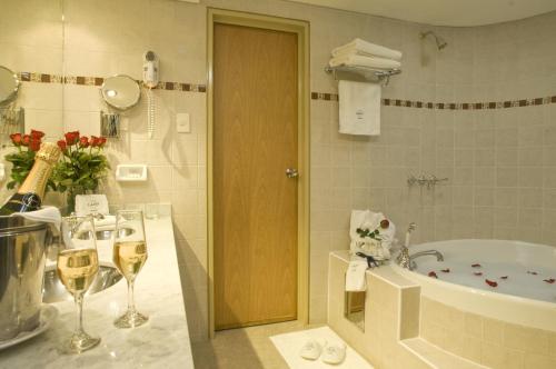 een badkamer met een bad en een douche met glazen wijn bij Land Express Neuquén in Neuquén