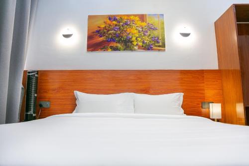 a bedroom with a bed and a painting on the wall at Hotel Totara in Dar es Salaam