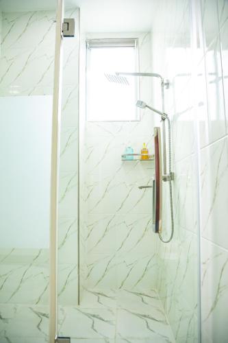 a shower in a bathroom with white marble tiles at Hotel Totara in Dar es Salaam