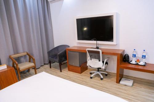 a room with a desk with a television and a chair at Hotel Totara in Dar es Salaam