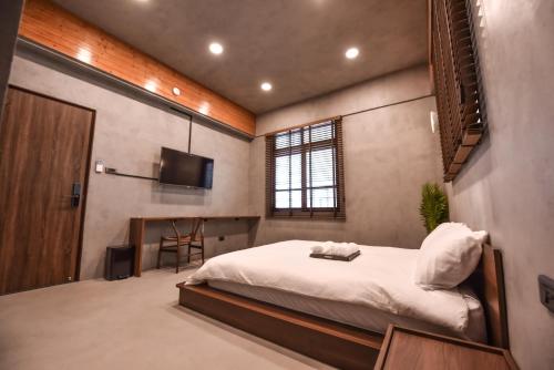 a bedroom with a bed and a flat screen tv at Eryang Homestay in Tainan