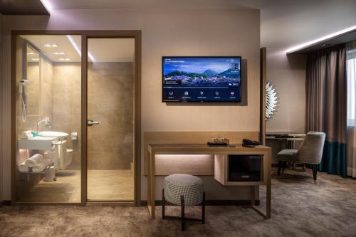 baño con escritorio y TV en la pared en -- ESTE PARK HOTEL -- part of Urban Chic Luxury Design Hotels - Parking & Compliments - next to Shopping & Dining Mall Plovdiv en Plovdiv