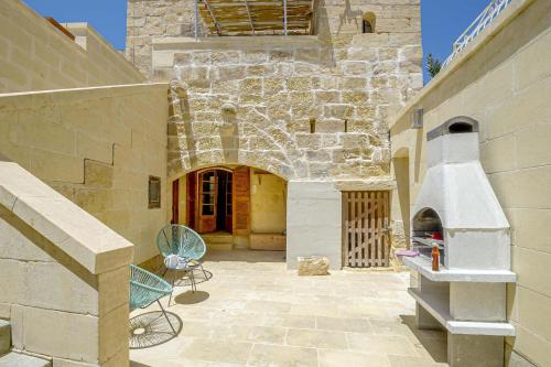 an outdoor patio with a stone building with an oven at Oleandra Holiday Home in Għasri