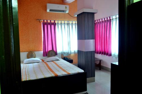 a bedroom with a bed with pink curtains at hotel sagnik in Murshidābād
