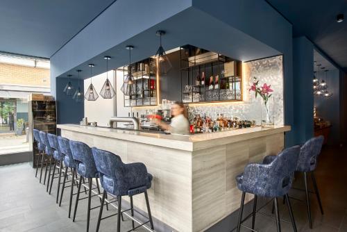 a woman sitting at a bar with blue bar stools at June Six Hotel Berlin City West in Berlin