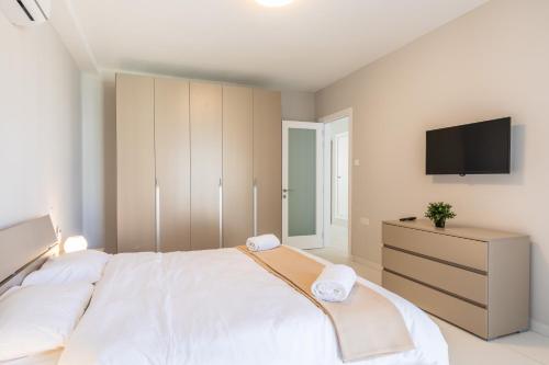 a bedroom with a large white bed and a tv at New & central located 3 Double bedroom apartment - Close to all amenities in Is-Swieqi