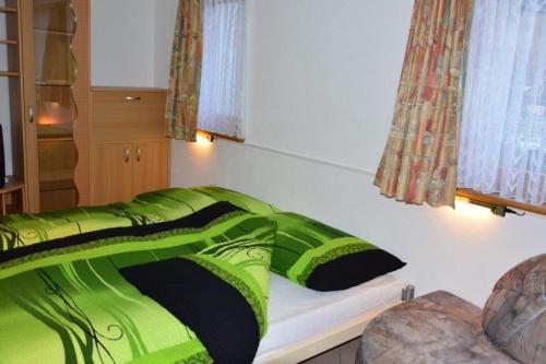 Bett mit grüner Decke in einem Zimmer in der Unterkunft Villa Kuntner Bund in Tschierv