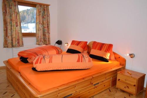 a bedroom with a bed with orange sheets and pillows at Villa Kuntner Bund in Tschierv