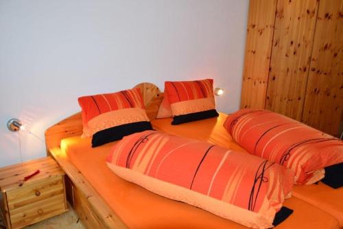 a bedroom with two beds with orange sheets and pillows at Villa Kuntner Bund in Tschierv