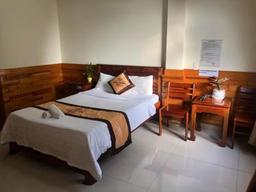 a bedroom with a bed and a table and chairs at Hoàng Gia Bảo Hotel in Kon Tum