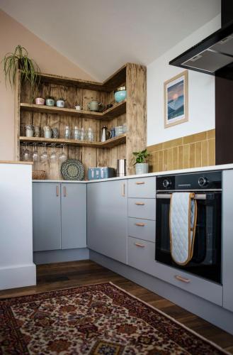 a kitchen with white cabinets and a black oven at Swn Y Don in Haverfordwest