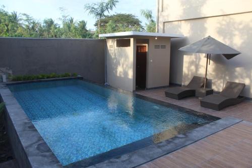 a swimming pool with two chairs and an umbrella at Grand Kuta Hotel in Kuta Lombok