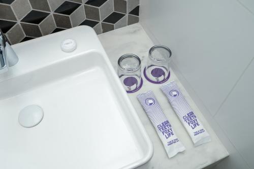 - un lavabo avec deux brosses à dents et deux tasses sur un comptoir dans l'établissement FOX Lite Hotel Samarinda, à Samarinda