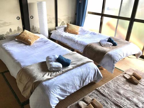 a room with two beds with pillows on them at Astuto Riders House in Annaka