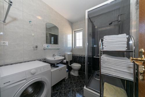ein Badezimmer mit einer Waschmaschine und einem Waschbecken in der Unterkunft "Mare et Sol" apartments in Sveti Filip i Jakov