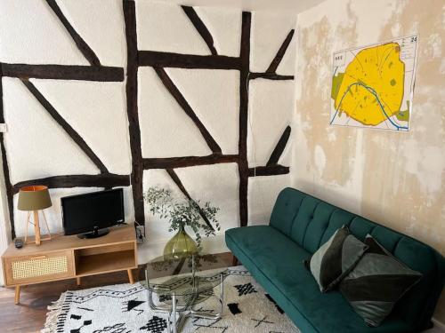 a living room with a green couch and a tv at Moulins centre : Appartement N*6 in Moulins