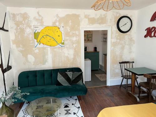 a living room with a green couch and a clock on the wall at Moulins centre : Appartement N*6 in Moulins