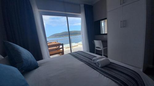 a bedroom with a bed with a view of the ocean at Phoenix Lodge and Waterside Accommodation in Knysna