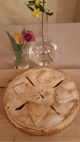 una torta seduta su un tavolo con un vaso di fiori di Casa Marinelli a Farra di Soligo