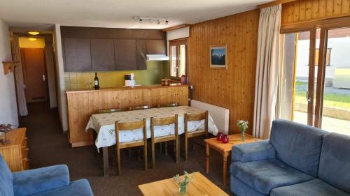ein Wohnzimmer mit einem Tisch und einer Küche in der Unterkunft Greppons MOUNTAIN & RESTFUL apartments by Alpvision Résidences in Veysonnaz