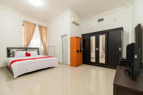 um quarto com uma cama e uma televisão de ecrã plano em RedDoorz Syariah near Universitas Putra Indonesia Padang em Kampungdurian