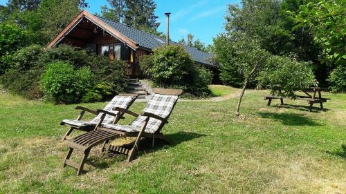 4 sillas de madera sentadas en el césped frente a una casa en Chalet Barvaux met grote tuin, en Durbuy