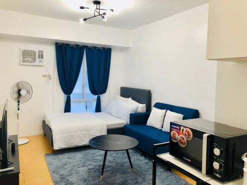 a hotel room with a bed and a blue couch at Avida Tower Sucat, comfortable studio type in Manila