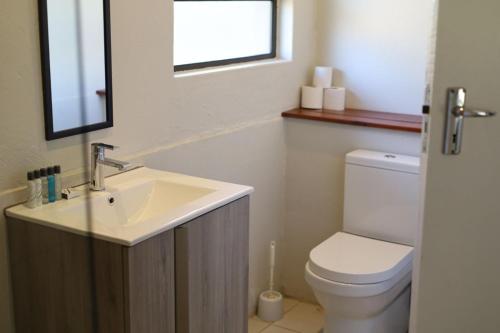 een badkamer met een wastafel, een toilet en een raam bij Waterberg Game Lodge in Bela-Bela