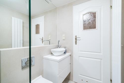 Baño blanco con lavabo y espejo en E-Stay Noclegi w Bydgoszczy, en Bydgoszcz