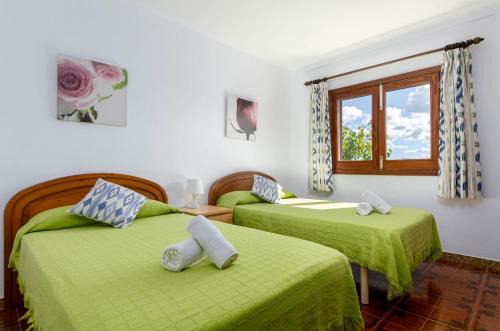 a bedroom with two beds with green sheets and a window at YourHouse Ca Na Teulera, villa with private pool in Can Picafort