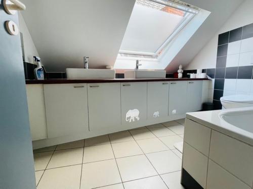 a bathroom with white cabinets and a sink and a window at Down Town Spacious Loft with Private Parking in Brussels
