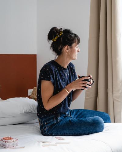 a woman sitting on a bed holding a remote control at Le Patio - Vallée d'Aspe in Bedous