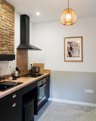 a kitchen with black cabinets and a stove top oven at Le Patio - Vallée d'Aspe in Bedous