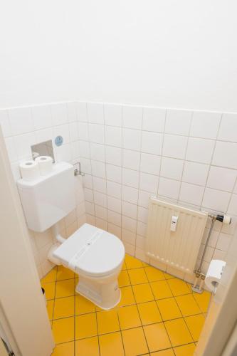 a bathroom with a white toilet and a yellow floor at Zum Grazer Uhrturm in Graz