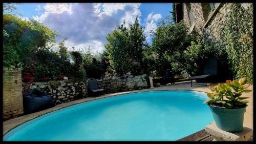 une grande piscine bleue à côté d'un mur en pierre dans l'établissement Les Jardins de Kuz - Baleine, à Bernin