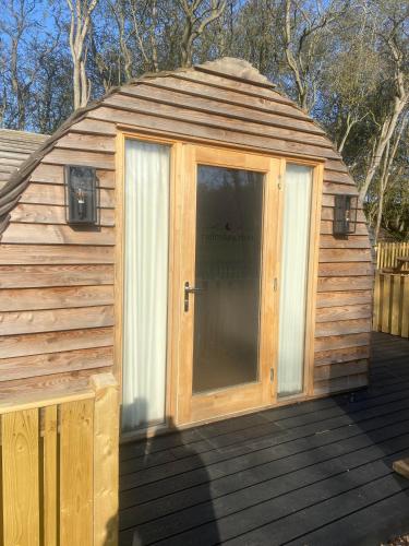 a large wooden building with a door on a deck at Cliff Stud Retreat - Luxury lodges and cosy cottages in Helmsley
