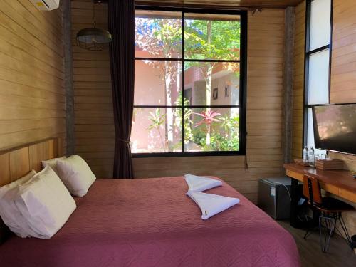 a bedroom with a bed and a desk and a window at Likita Resort in Ban Phe