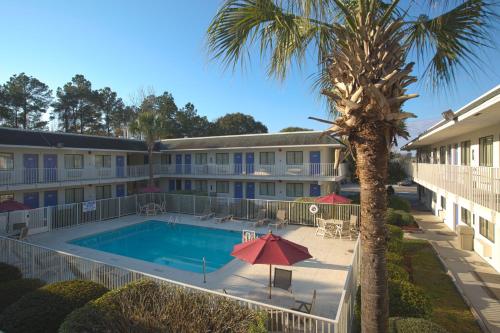 a view of a hotel with a pool and a palm tree at North Charleston Lodge in Charleston