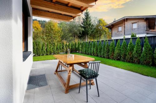un patio con una mesa de madera y 2 sillas en Garten Suite Kirchberg by Alpine Host Helpers en Kirchberg in Tirol
