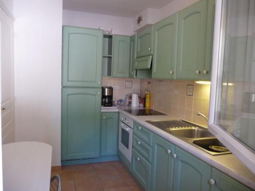 une cuisine avec des armoires vertes et un évier dans l'établissement Villa domaine de la Pinède Golfe Saint Tropez, à La Garonnette-Plage
