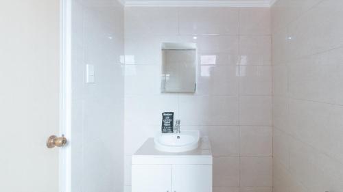 a white bathroom with a sink and a mirror at RedDoorz at The Providence Tower in Manila