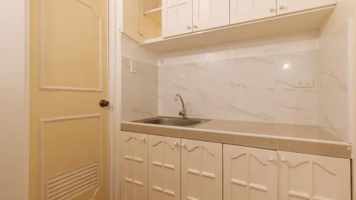 a kitchen with white cabinets and a sink and a door at RedDoorz at The Providence Tower in Manila