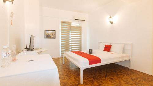 a white bedroom with a bed and a desk at RedDoorz at The Providence Tower in Manila