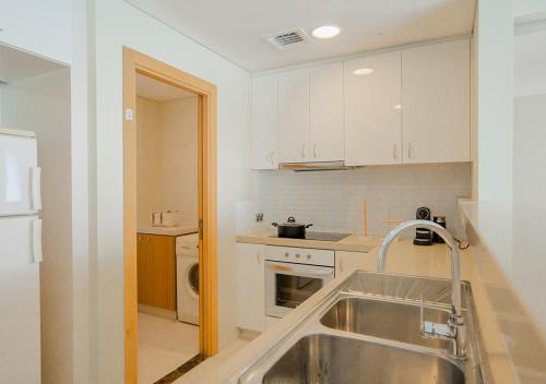 a small kitchen with a sink and a stove at Nasma Luxury Stays - Serene Apartment With Balcony Steps From The Sea in Abu Dhabi