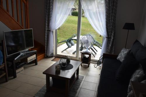 a living room with a large window and a tv at location maison à Cajarc 46160 (Lot) in Cajarc