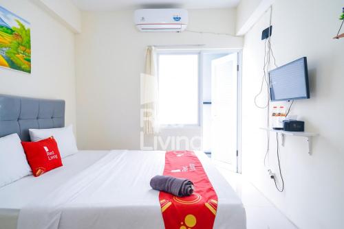 茂物的住宿－RedLiving Apartemen Bogorienze Resort - Skyland Tower A，一间卧室配有一张带红色枕头的白色床和电视。
