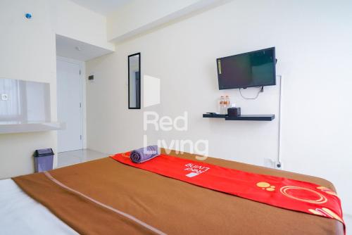 a room with a bed with a tv on the wall at RedLiving Apartemen Bogorienze Resort - Skyland Tower A in Bogor